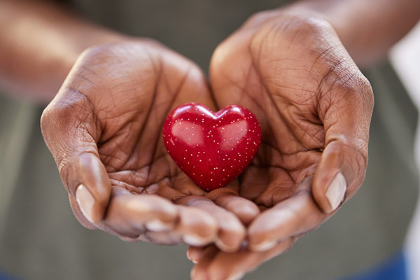 Two hands holding a red heart