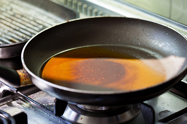 A black frying pan with a thin layer of oil on a stove burner.