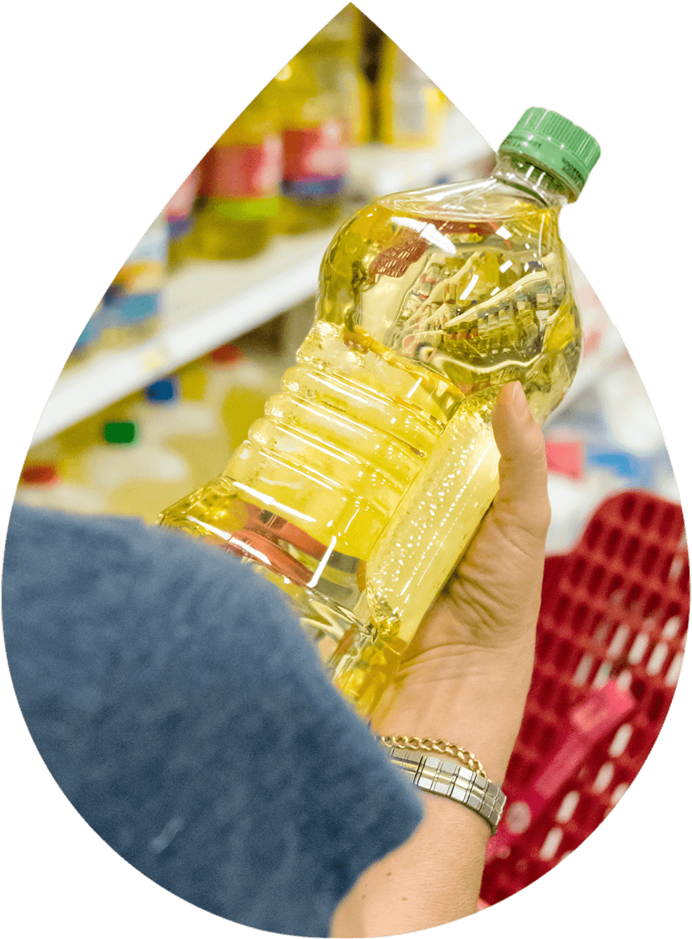 A person holding a bottle of cooking oil in a grocery store aisle.